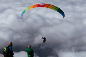 A man paraglides above clouds